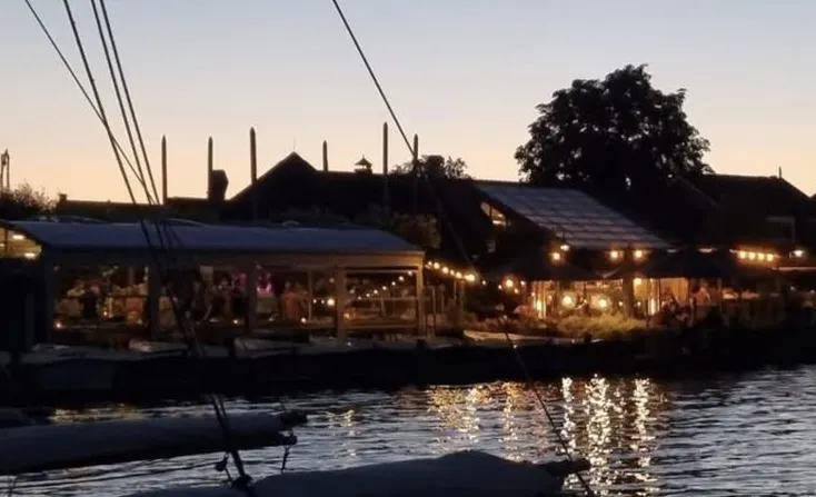 Restaurant Tijsterman bij zonsondergang, verlichte serre en terras aan het water
