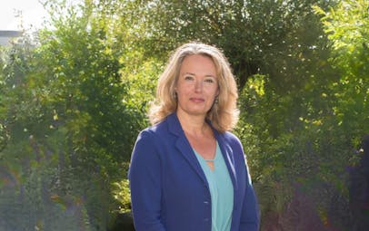 Vrouw met blond haar in groene omgeving.