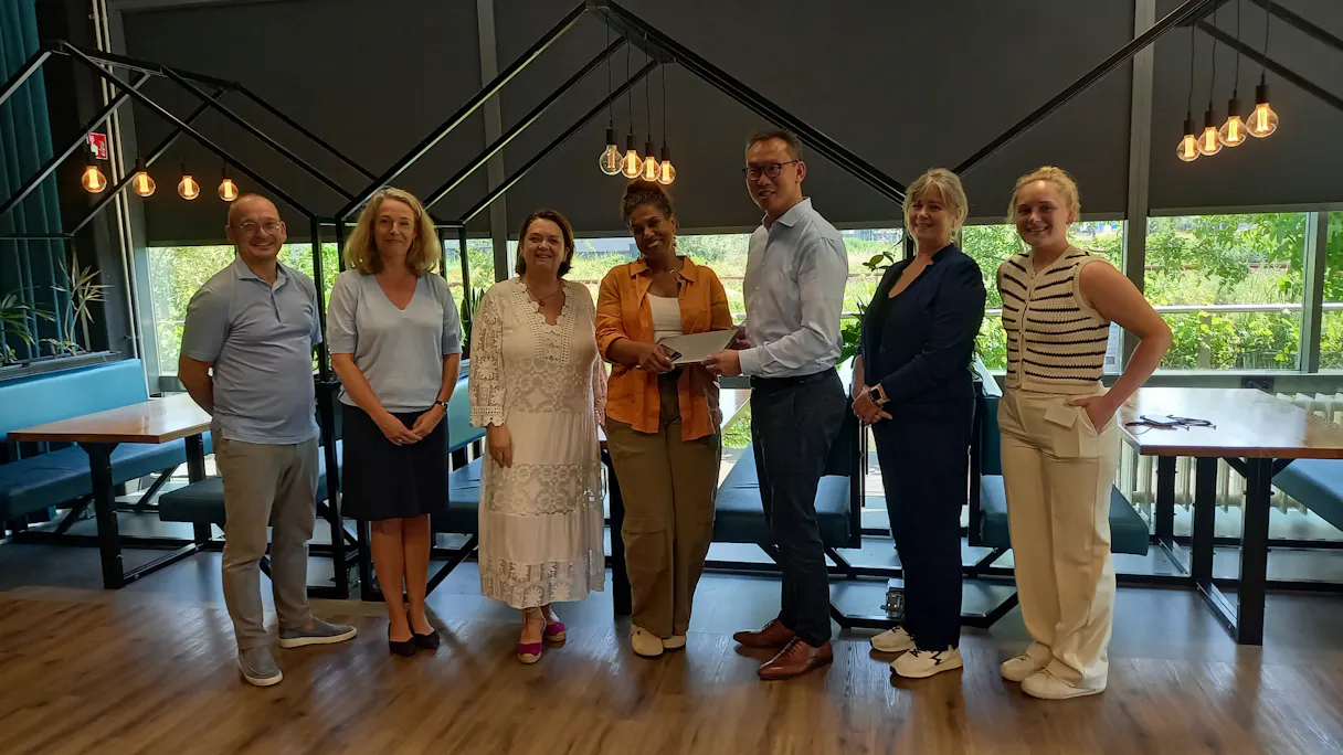 Groep mensen poseert in een sfeervolle eetzaal.