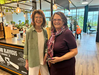Twee lachende vrouwen in een gezellig café.