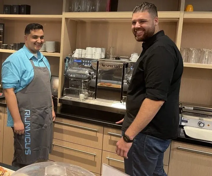 Twee mannen bij een koffiezetapparaat in een keuken.