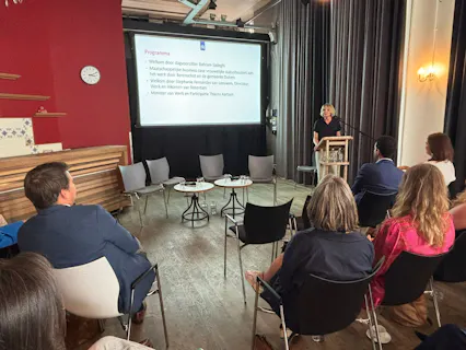 Presentatie met spreker en publiek in een zaal.