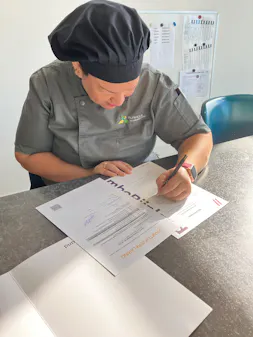 Kok schrijft een formulier aan tafel.