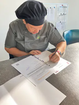 Kok schrijft een formulier aan tafel.