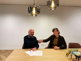 Twee mensen tekenen een overeenkomst aan tafel.