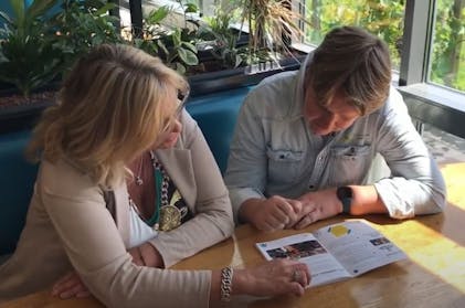 Twee mensen bekijken samen een brochure.