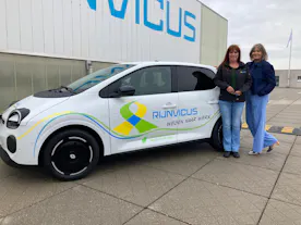 Twee vrouwen naast een auto met Rĳnvirus-logo.
