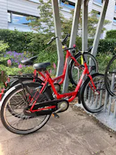 Rode elektrische fietsen staan geparkeerd bij een fietsenrek.