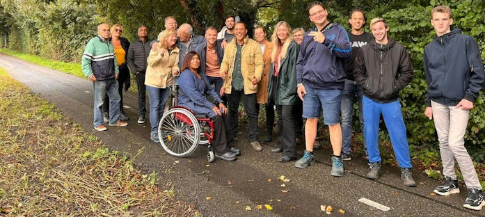 Groep mensen op een pad, met rolstoelgebruikster.