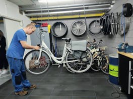 Man repareert een fiets in een werkplaats.