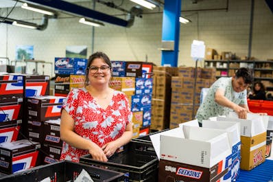Vrouw met bloemetjesblouse in magazijn met dozen.