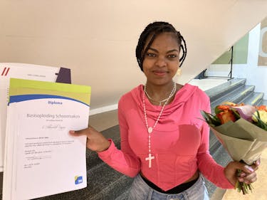 Jonge vrouw met diploma en bloemen in de hand.