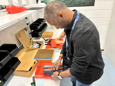 Man assembleert een drone in een werkruimte.