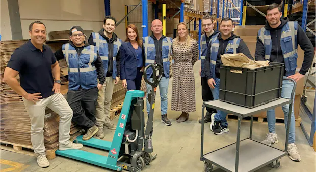 Groep mensen in een magazijn met een palletwagen.