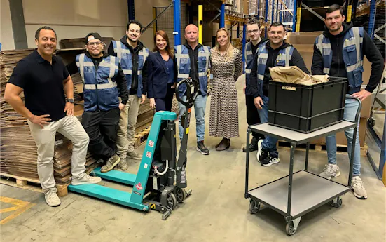 Groep mensen in een magazijn met een palletwagen.