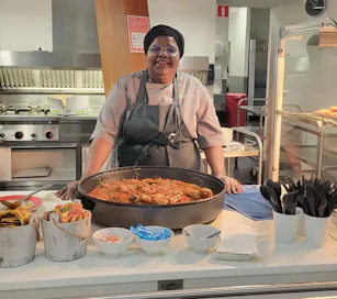 Vrouw met grote pan eten in professionele keuken