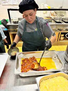 Kokkin bereidt lasagne in een professionele keuken.
