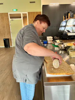 Medewerker smeert beleg op een broodje