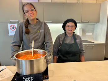 Twee koks met een pan soep in de keuken