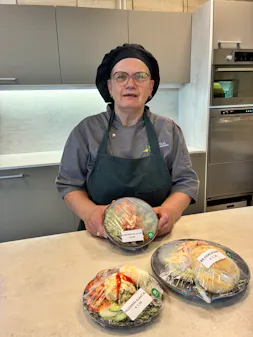 Kok met drie verpakte maaltijden in een keuken