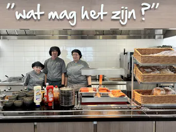 Keukenpersoneel achter de toonbank met eten en broodmanden