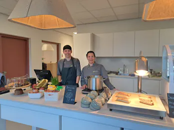 Twee medewerkers achter een toonbank met gebak en broodjes