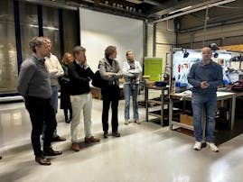 Groep mensen in een workshopruimte, iemand spreekt.