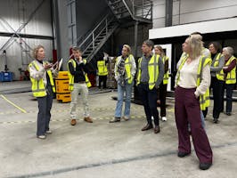 Groep mensen in veiligheidsvesten in een magazijn.