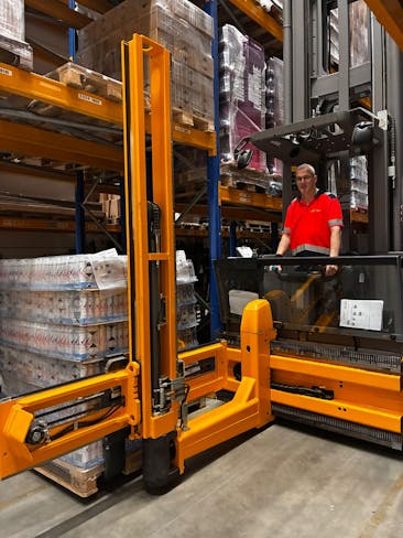 Man bestuurt een gele heftruck in een magazijn.