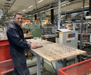 Man staat aan een werkbank in een fabriek.