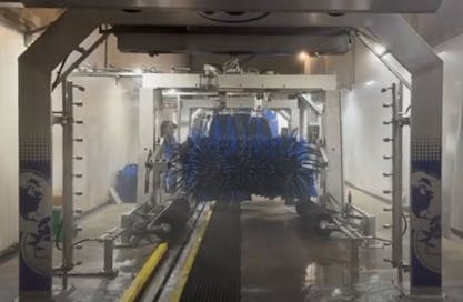 Auto in wasstraat met draaiende borstels.