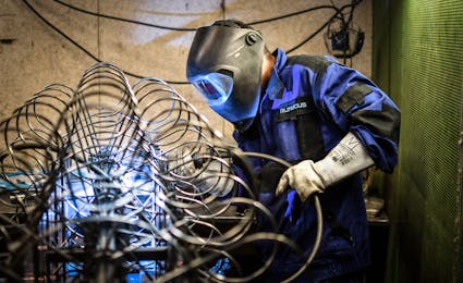 Lasser werkt met metalen buizen en beschermhelm.