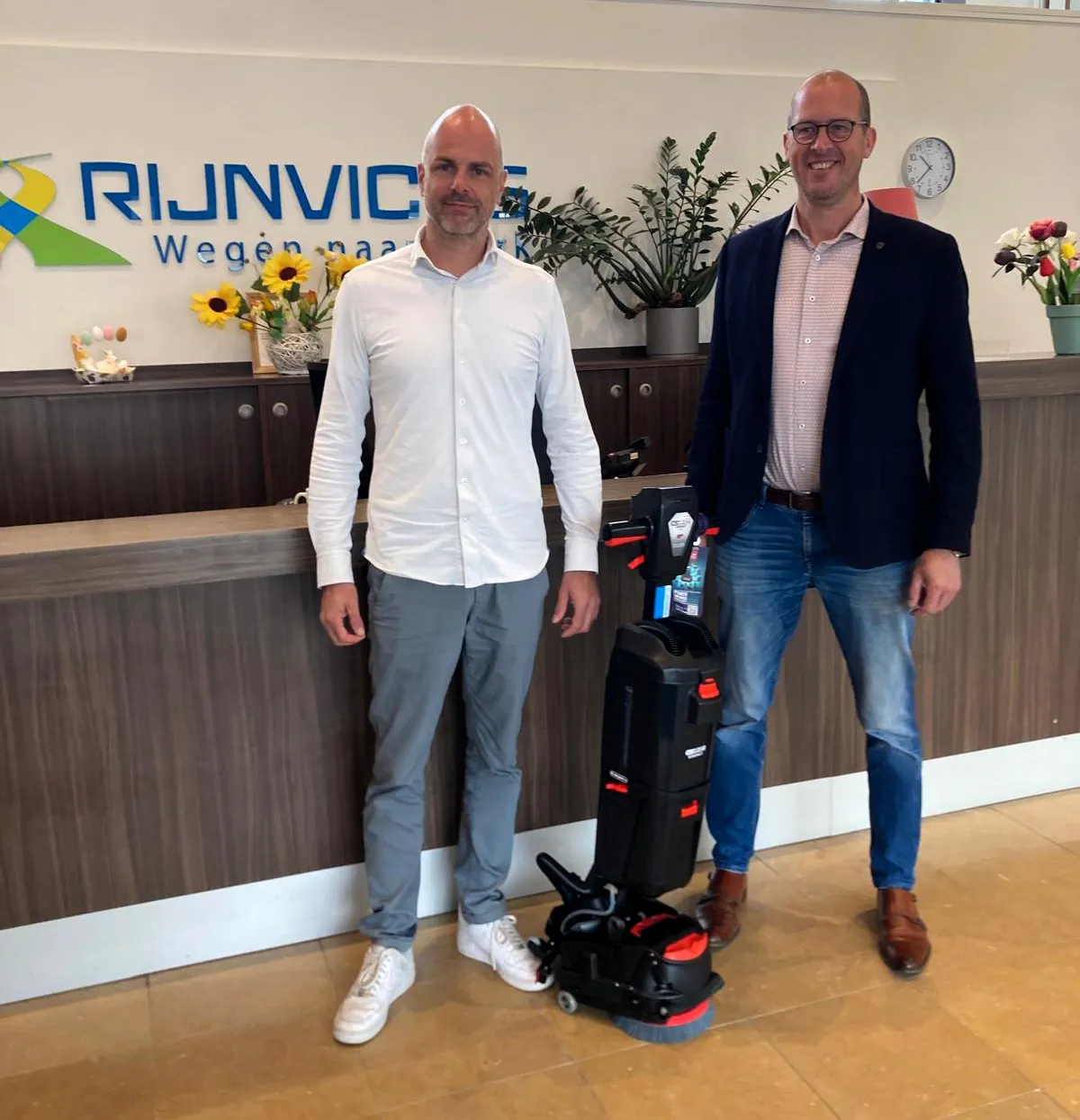 Twee mannen naast een vloerreiniger bij de receptie.