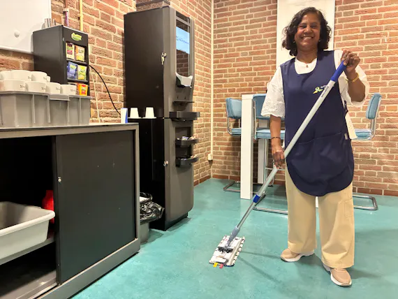 Vrouw met een mop in een moderne ruimte.