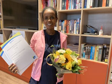 dame met bloemen en diploma schoonmaak in haar hand