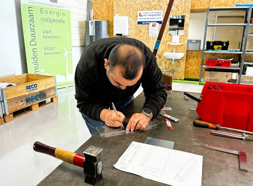 Man tekent op een plastic plaat in een werkruimte.