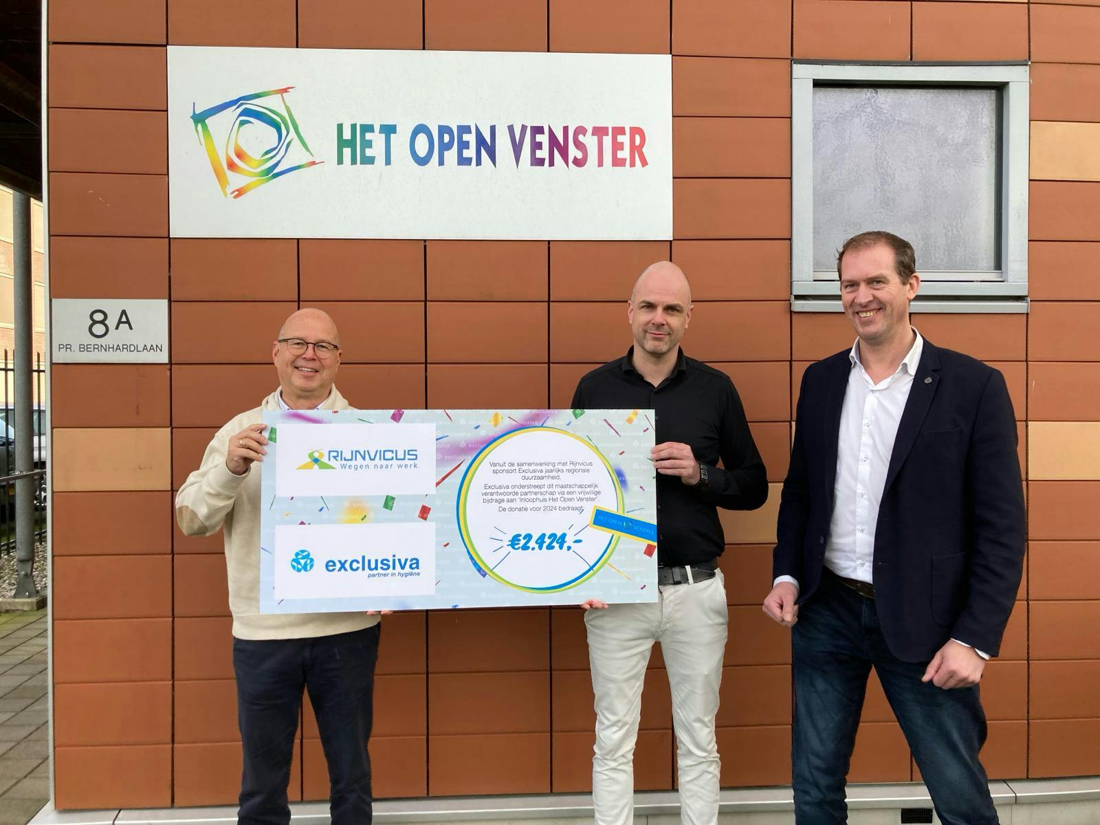 medewerkers van het Open Venster, Exclusiva en Rijnvicus staan op de foto met cheque