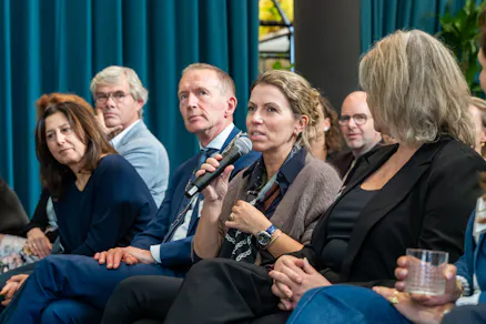 Panelleden luisteren terwijl een vrouw spreekt.