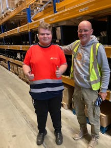 Twee mannen in magazijn, beide geven duim omhoog.