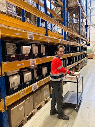 Jongeman met een kar in een magazijn.