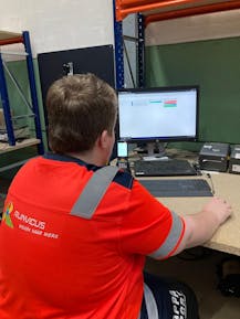 Jongen in rood shirt werkt achter computer.