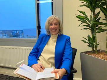 Glimlachende vrouw met documenten naast een plant