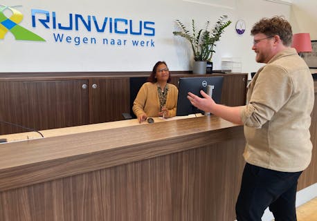 man staat bij receptioniste aan de balie