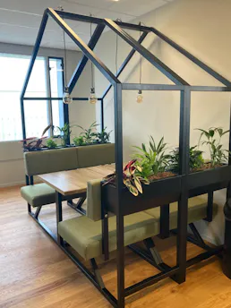 Groene zithoek met planten in een glazen huis.