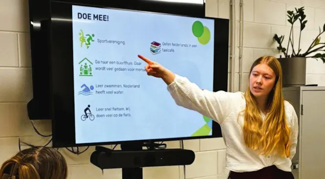 Een meisje wijst naar een presentatie in een klas.