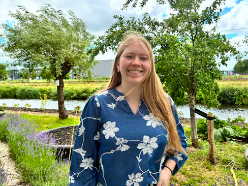 Jonge vrouw in een bloemenblouse, tussen bomen.