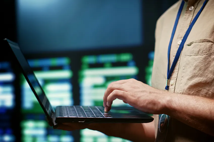 Domain Portfolio Manager looking at laptop with servers on the background